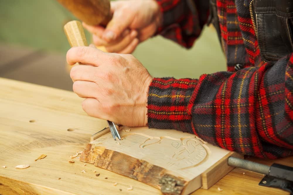 man wood carving by hand with chisel