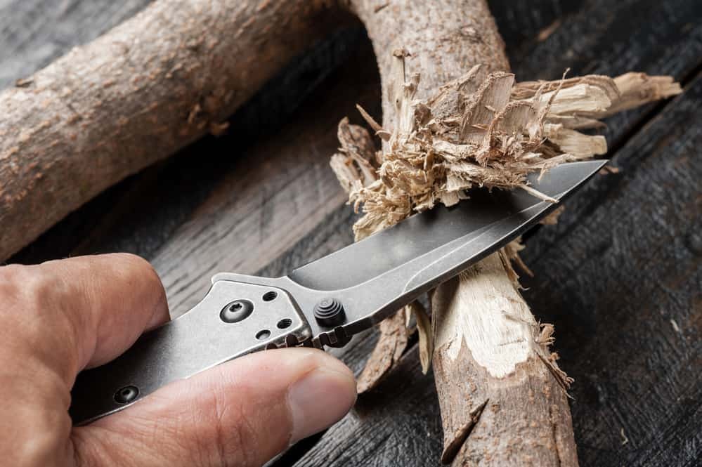 whittling a piece of wood with a stainless steel pocketknife with blackwash finish on blade and handle