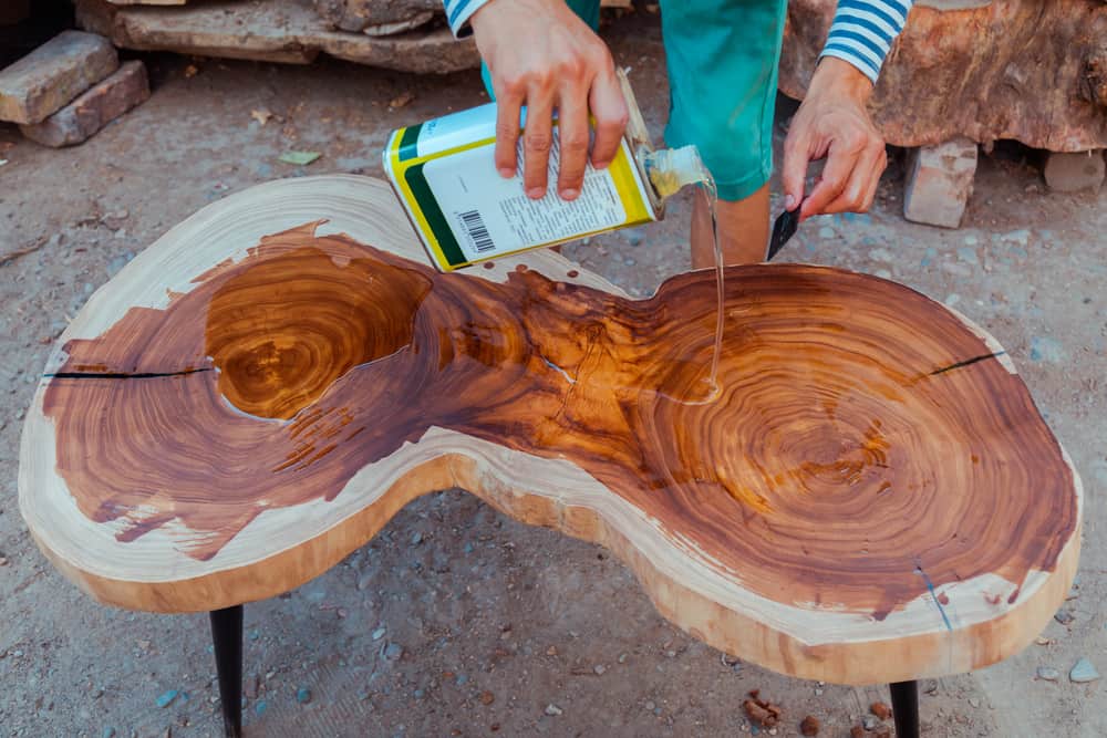 Carpenter pouring linseed oil on wood